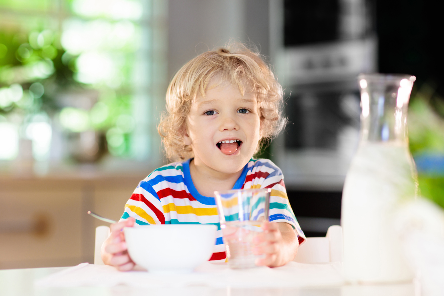 Child eating breakfast. Kid with milk and cereal.